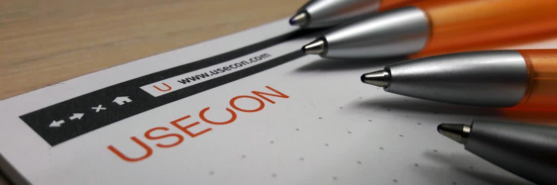 USECON Logo auf einem Block mit Kugelschreibern